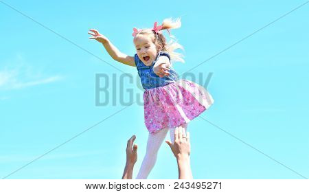 Happy Childhood. Father Tosses Up To The Sky His Daughter. Cheerful Girl On The Sky Background.