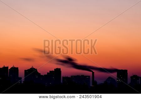 Cityscape With Dramatic Sky  Sunset. Silhouette Of Buildings And Smoking Pipes. Urban Industrial Cit