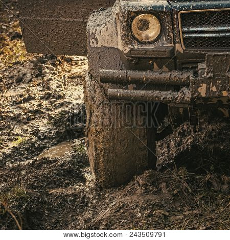 Dirty Offroad Tire Covered With Mud. Wheel In Deep Rut Goes Through Mud And Leaves Trail. Extreme En