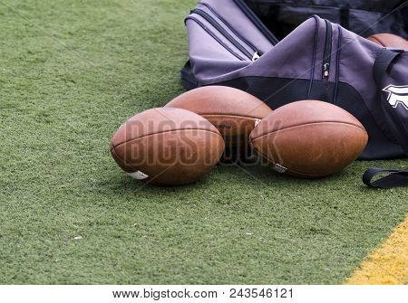 Footballs On The Field With Purple Duffle Bag