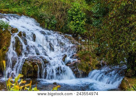 The concept of ecological, pedestrian and photo tourism. Slunj, Croatia. Cascade waterfalls are lit by sunset rays. Amazing park above the water channels of the Korana River
