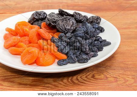 Fragment Of The White Dish With Dark-colored Raisins, Dried Plums And Dried Apricots Closeup At Sele