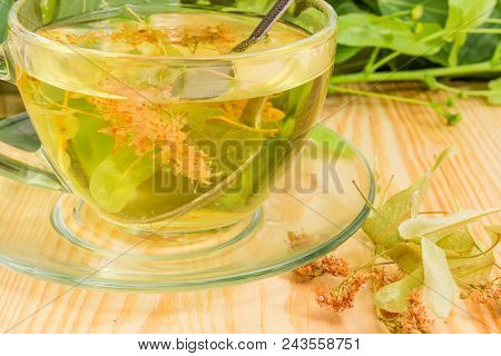 Fragment Of The Transparent Glass Cup With Linden Flower Tea And Dried Linden Flowers Beside Closeup