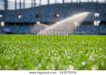 Grass On Stadium In Sunlight. Closeup Of A Green Football Field. Wet Stadium Grass In The Morning Li