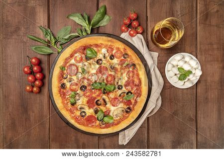 An Overhead Photo Of A Pepperoni Pizza With A Glass Of White Wine, Basil Leaves, Cherry Tomatoes And