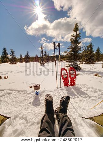 Lunch Time During Winter Trail. Camping On Snow And Cooking. Red Snowshoes And Trekking Poles Stand 