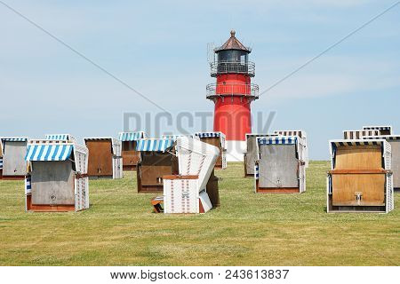 Dike Or Dyke With Hooded Beach Chairs And Lighthouse In Buesum, Germany