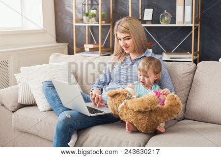 Happy Beautiful Business Mom Working On Laptop In Home Office While Her Cute Baby Playing With Toys.