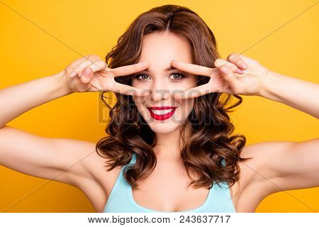 Portrait Of Creative Positive Girl With Modern Hairdo Showing V-signs With Two Hands Near Eyes Looki