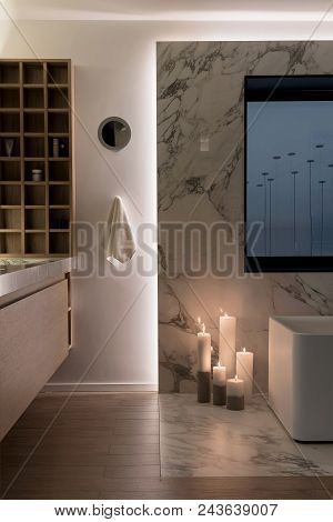 Illuminated Modern Bathroom With White Wall And A Parquet On The Floor. There Is A Tiled Zone With A