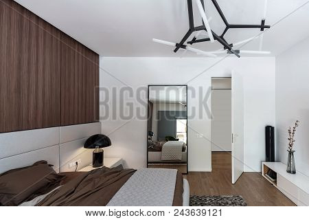 Bedroom In A Modern Style With White Walls And A Parquet On The Floor. There Is A Bed With A Brown L