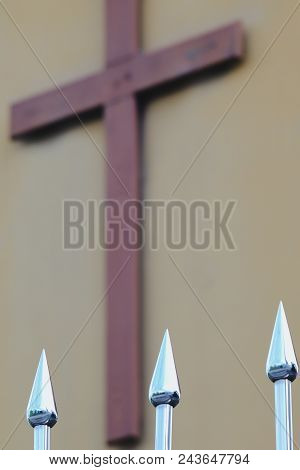 Iron Spearhead Fence With Cross In Background.