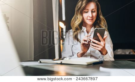 Front View. Young Smiling Businesswoman Is Sitting In Office At Table In Front Of Computer, Using Sm