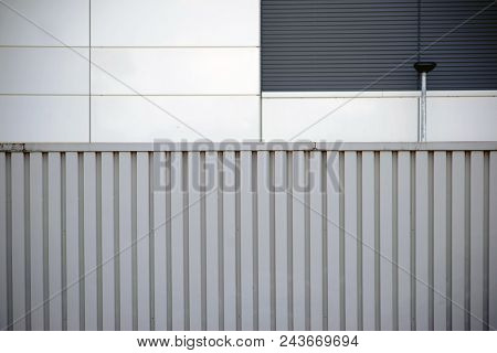 A Noise Barrier And Barrier Made Of Corrugated Steel In Front Of A Modern Facade Of Metal Panels.