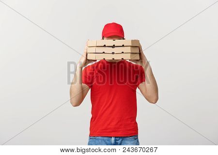 A Deliveryman Hidden Behind A Large Stack Of Pizza Boxes He Is Carrying. Isolated Over Grey Backgrou