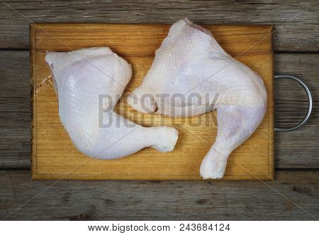 Raw Uncooked Chicken Legs On A Wooden Cutting Board , Meat With Ingredients For Cooking. Top View
