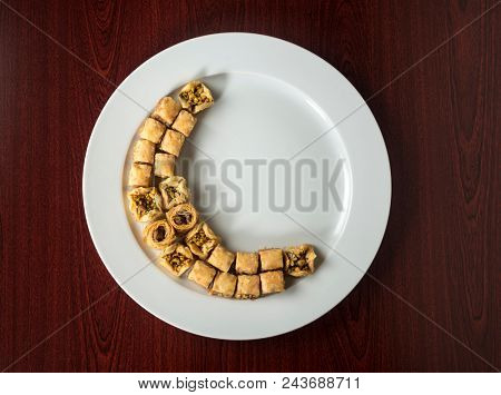 Baklava arranged in moon shape on white plate. Middle-eastern festive food - An idea.