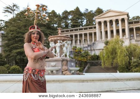SOCHI, RUSSIA - JUL 07, 2017: Dancer (with model release) dancing belly dance with chandelier on head on background Matsesta, largest medical balneological complex in Russia