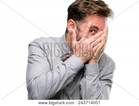 Middle age man, with beard and bow tie smiling having shy look peeking through fingers, covering face with hands looking confusedly broadly isolated over white background