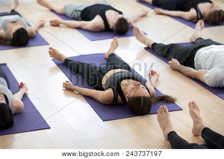 Group Of Young Sporty People Practicing Yoga Lesson, Doing Savasana Pose, Corpse Exercise, Dead Body