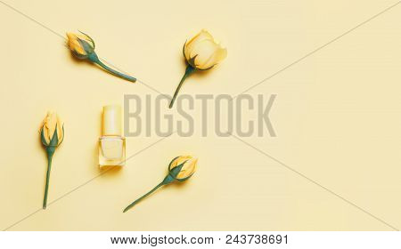 Nail Polish Bottle And Yellow Roses On Yellow Background. Trendy Manicure Concept, Pure Colors.