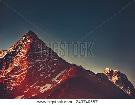 The snow-capped Thamserku Mountain, Himalayas. Eastern Nepal. Perfect background in the contrast blue and red shades for the various kinds of collages and illustrations.