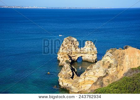 Elevated View Of The Coastline And A Natural Arch In The Ocean And A Boat To The Centre, Praia Da Do