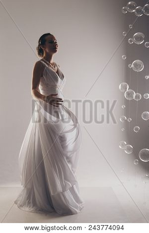 Girl In White With Her Hands Up. The Bride In A Dress In Greek Style. Brunette In Pearl Jewelry. The