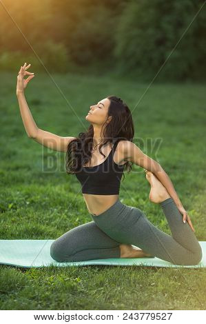Woman Practicing Yoga Performing Yoga-asanas. Young Attractive Slim Girl In Bodysuit Relaxing And Do