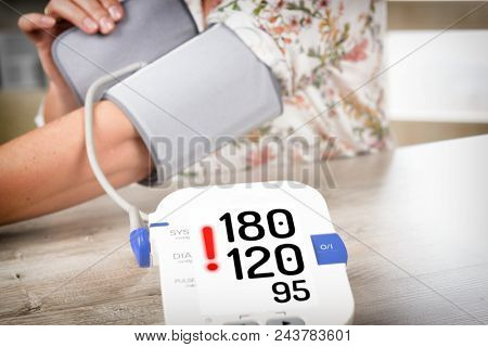 Women's hand with blood pressure monitor cuff. Checking blood pressure at home concept