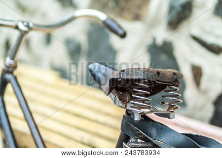 An Old Bicycle Seat With A Spring Shock Absorber. Vintage Bicycle On The Stone Wall Background.