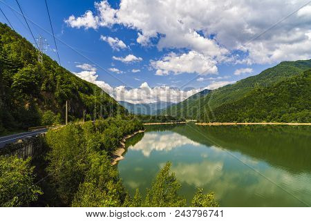 Landscape With Olt River In Romania Surrounded By Forest And Mountains