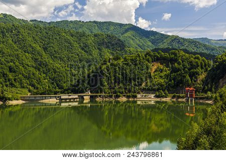 Landscape With Olt River In Romania Surrounded By Forest And Mountains