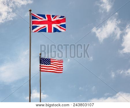 British And American Flags Flying On Flagpoles With Blue Skies On A Sunny Day
