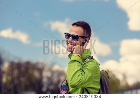 Smiling Happy Tourist Talking On Phone With Bluetooth Headset Device