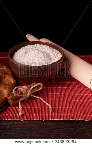A Bowl With Flour And Apricot Cake On A Wooden Background On Black