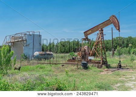 Working Pump Jack Pumping Crude Oil At Oil Drilling Site In Rural Usa