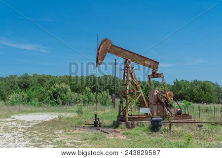 Working Pump Jack Pumping Crude Oil At Oil Drilling Site In Rural Usa