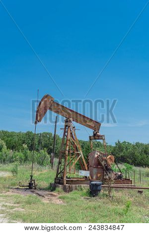 Working Pump Jack Pumping Crude Oil At Oil Drilling Site In Rural Usa
