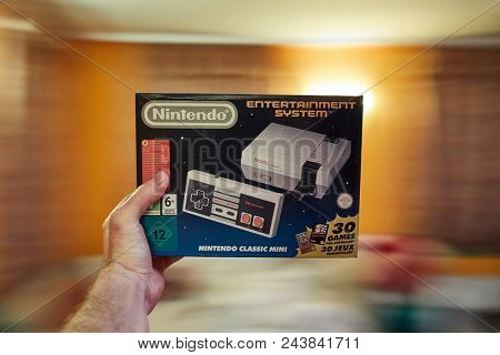 BUDAPEST, HUNGARY - DECEMBER 10, 2017: Nintendo NES classic edition video game console, box geld in hand. Modernized version of the original with preinstalled games