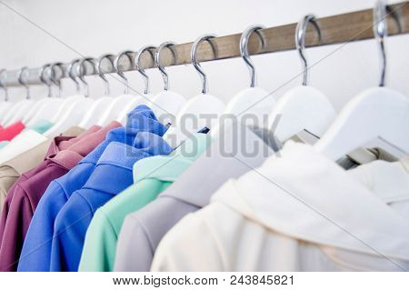 Colorful softshell coats on rack with hangers. Fashion conception.
