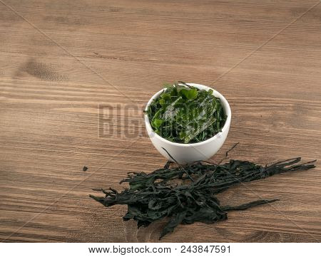 Heap Of Dry Wakame Seaweed On Wooden Background. Healthy Algae Food With Place For Text