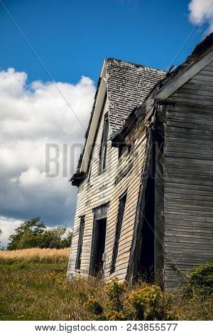 Side view of a derelict house in rural New Brunswick, Canada. Side view showing the front facade detatched from the remainder of the structure.
