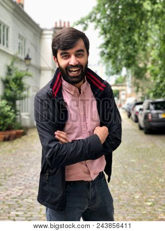 Handsome casual Indian man laughing in a London mews