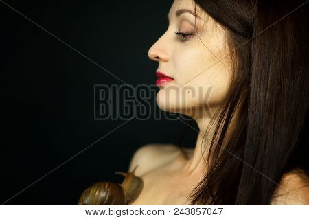 Side View Of Young Woman Receiving Snail Neck Massage In Studio On Black Background.
