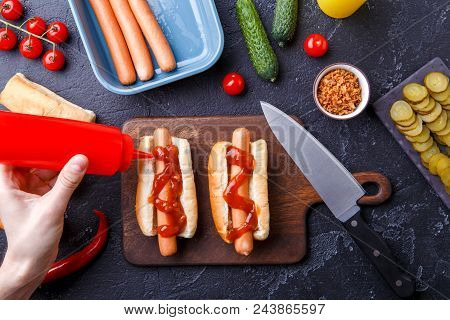 Picture On Top Of Table With Ingredients For Hot Dogs, Cutting Board, Man's Hands