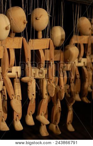 Several Wooden Puppets On Cords On Black Background