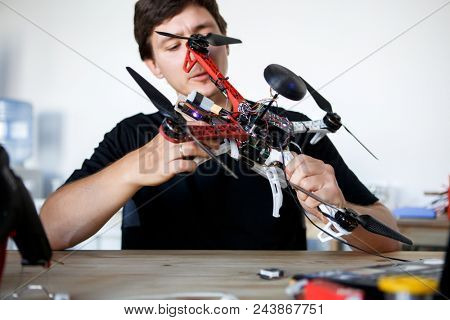 Picture of man fixing square copter at table