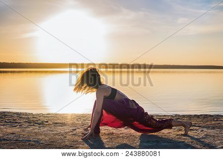 Silhouette Woman On The Beach At Sunset Doing Yoga Asana. Morning Natural Stretch Warm-up Training