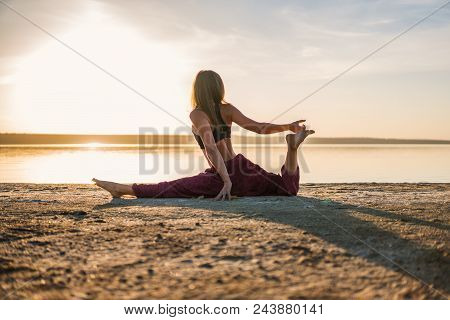 Silhouette Woman On The Beach At Sunset Doing Yoga Asana. Morning Natural Stretch Warm-up Training